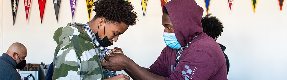 Mentor teaching student how to tie a necktie properly