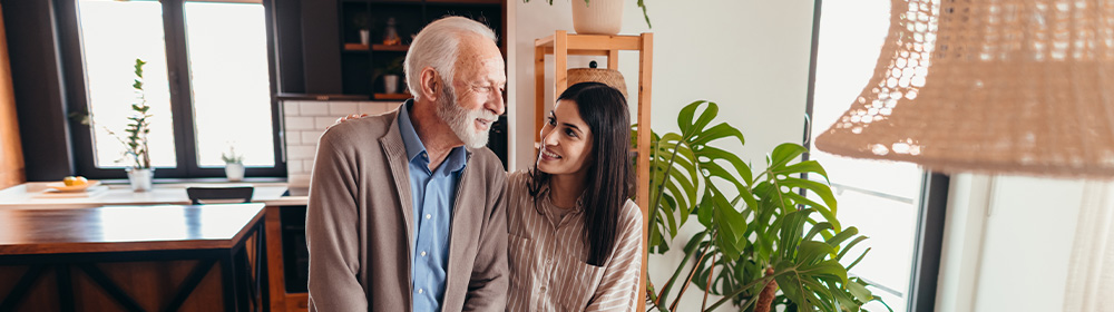 Young woman assists an older gentlemen in his home.