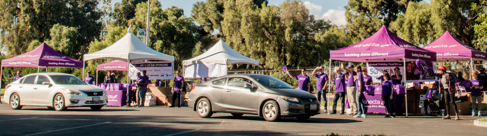 Cars lined up to pick up food orders under tents.