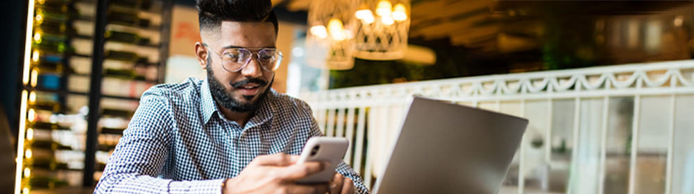Young man looks at his mobile phone inside a coffee shop.