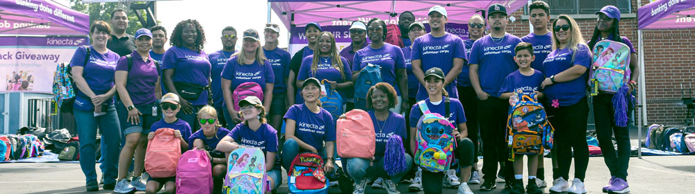 Group of employees and community members holding up backpacks and smiling.