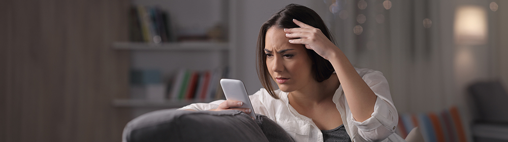 Woman stares at phone concerned.