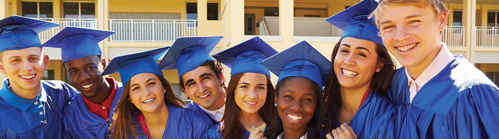 Students in caps and gowns smiling on graduation day.