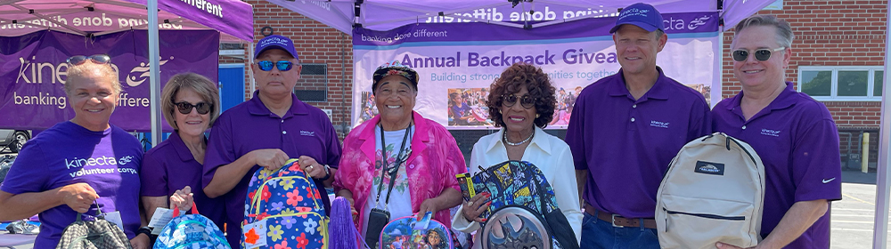 Employees and volunteers pose with backpacks prepared for students this year.